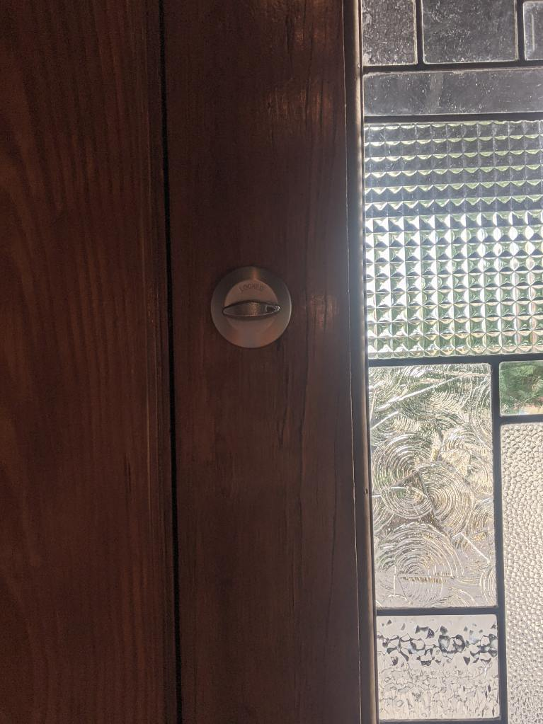 Interior thumbturn on wood door beside decorative glass